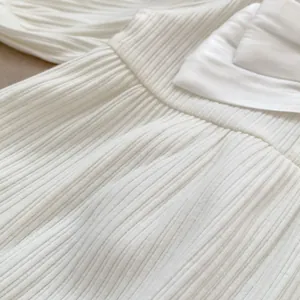 Detailansicht eines Baby-Stramplers mit weißem Rippstrick-Stoff und gesmokter Textur