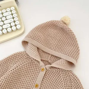 Detalle del cárdigan con capucha para bebé con textura gruesa y un pompón suave en la capucha