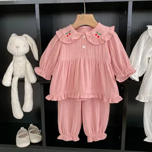 Détail d'un ensemble pyjama bébé en gaze de coton rose avec cerise brodée et volants