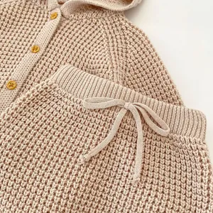 Detalle de conjunto de punto para bebé con textura de gofre y botones de madera