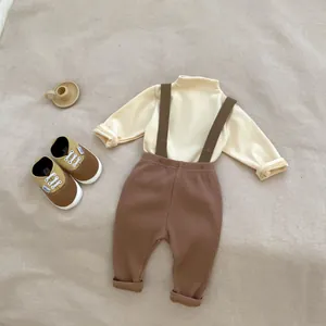 Flat lay of baby minimalist turtleneck long sleeve top with ribbed suspender trousers