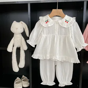 Détail d'un pyjama en gaze de coton pour bébé avec broderie cerise et col à volants