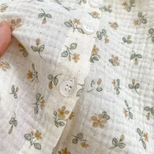 Detail of floral baby shirt with yellow flowers and white resin buttons texture