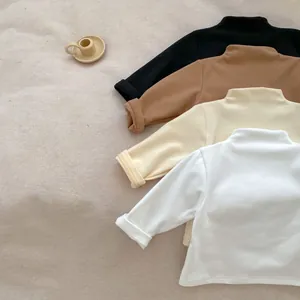 Detail of soft cotton kids mock neck base layers in earthy tones neatly stacked
