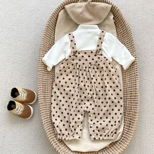 Flat lay of baby corduroy romper set with polka dots, matching beret and soft shoes