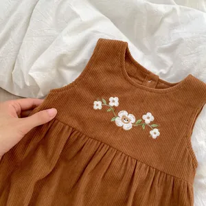 Detail of baby brown corduroy romper featuring delicate white floral embroidery work