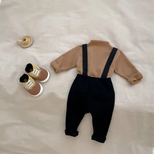 Flat lay of baby two-piece set with brown long sleeve top and black ribbed overalls