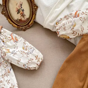 Flat lay of baby bodysuit with forest animal prints and brown corduroy pants