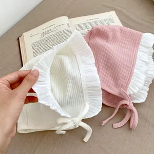 Makro-Detail von Babyhauben aus weicher Rippbaumwolle mit zarten Rüschenspitzenkanten