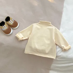 Detailed flat lay of cream-colored baby mock neck top with soft ribbed cotton texture