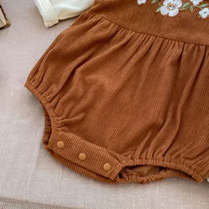 Detail of baby corduroy romper featuring daisy embroidery and snap buttons at the crotch