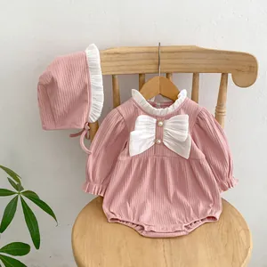 Detailansicht rosa Baby-Strampler mit weißer Schleife und Rüschenkragen auf Holzstuhl