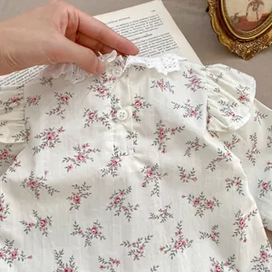 Dettaglio della camicia floreale per neonata in cotone con colletto in pizzo e bottoni