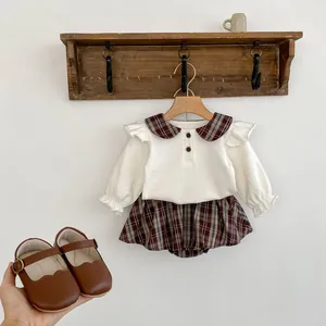 Detail eines Vintage-Peter-Pan-Kragens mit Karomuster auf einem Baby-Langarmshirt