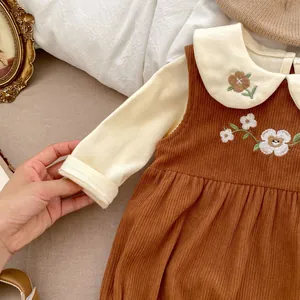 Detail of embroidered floral patterns on corduroy baby jumpsuit with a Peter Pan collar