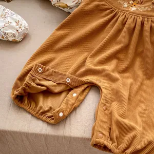 Detail of baby romper featuring corduroy texture, deer embroidery and snap buttons