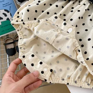 Detail of baby polka dot romper showing resin snap buttons and elastic leg openings