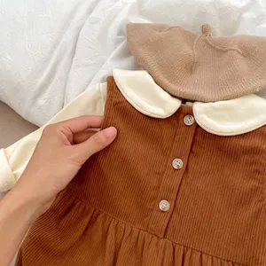 Detail of baby corduroy pinafore dress with Peter Pan collar and matching beret set