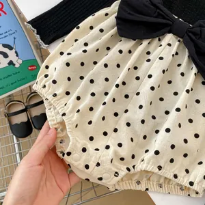 Detail of baby romper with black bow, polka dot print and snap buttons on metal grid
