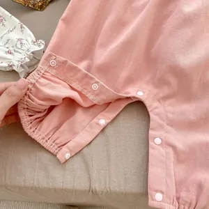 Dettaglio della salopette rosa per neonati con bottoni a pressione e polsini elastici