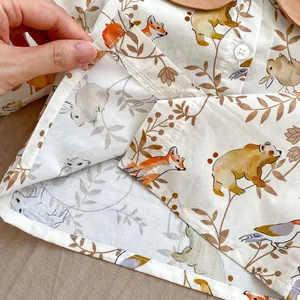 Detail of baby romper with cute forest animals print and white button on soft cotton