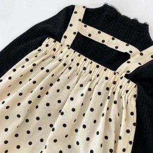 Detail of baby girl's black ribbed long sleeve top and polka dot suspender dress set