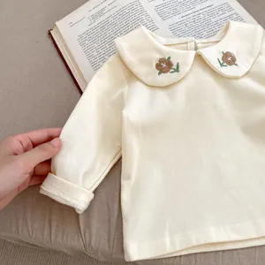 Detail of baby cream Peter Pan collar top with vintage floral embroidery and cotton fabric