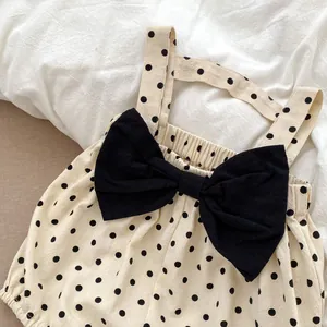 Detailed view of baby romper featuring classic black polka dots and a large bow accent
