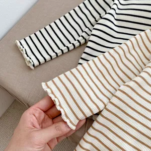 Detail of soft ribbed striped fabric with elegant lettuce edge cuffs on girls' tops