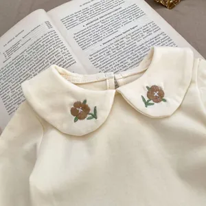 Detailed view of baby corduroy bodysuit with Peter Pan collar and floral embroidery
