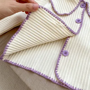 Detail der gerippten Strickjacke mit lila Wellenkanten und passenden runden Knöpfen