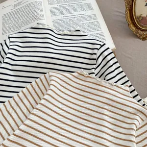 Detail of ruffle neck striped ribbed knit tops in black, white, and brown colors