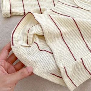 Vue macro d'un tissu en maille rayé crème avec coutures précises et texture douce