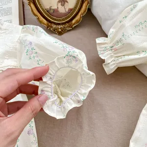Detail of floral baby bodysuit with elastic ruffled cuffs and white lace embroidery