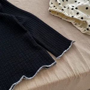 Close-up of black ribbed knit fabric with ruffle edge detailing for baby girl clothes