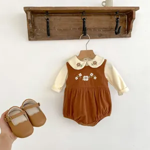 Detail of baby corduroy overalls with flower embroidery and matching leather shoes