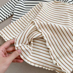 Detail of lettuce edge hem on striped long-sleeve shirts showing soft cotton texture