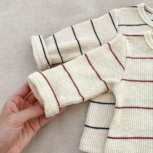 Détail des poignets en maille côtelée et du tissu rayé d'un pyjama pour enfants