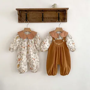 Detail view of baby floral romper and corduroy dungarees set hanging on wooden hangers
