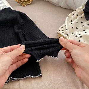 Detail of high elasticity black ribbed long sleeve top with white lettuce edge trim