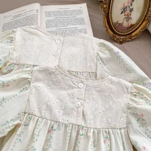 Detail of floral baby bodysuit with intricate lace embroidery and vintage buttons