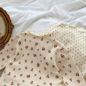 Detail of baby floral long sleeve top with frill neck and wave-edged cuffs in cream beige