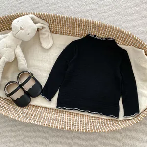 Detail of baby black ribbed long sleeve top with white ruffled lettuce trim on basket