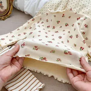 Detail of ruffle edges and red floral print on girls' soft long-sleeve cotton top