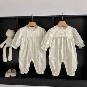 Detail view of floral baby rompers with lace trim and ruffled cuffs on wooden hangers