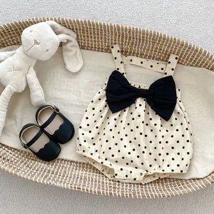 Detailed flat lay of beige polka dot baby bodysuit with black bow and Mary Jane shoes