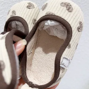 Close-up of baby walking shoes in cream corduroy fabric with brown heart pattern print