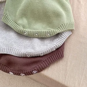 Dettaglio di pagliaccetti in maglia per neonati con bordi a coste e bottoni in resina in 3 colori