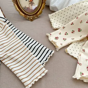 Close-up of ruffled cuffs on cotton ribbed baby shirts in various stripe and floral patterns