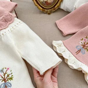 Makroansicht der floralen Stickerei und des Spitzenkragens an der rosa Babystrickjacke